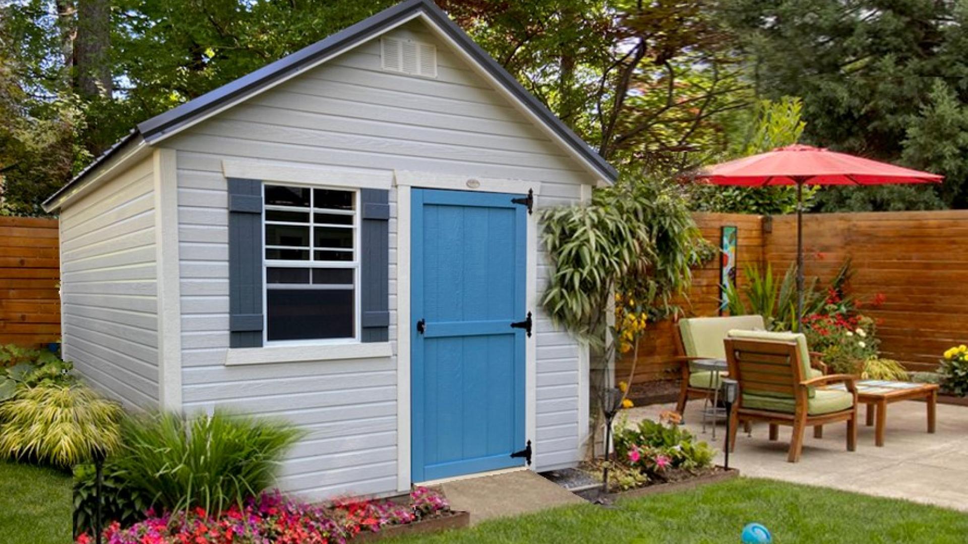 White garden shed with bright blue door in a stylish backyard