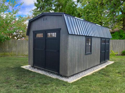 Signature high barn with grey wood siding, two sets of black double doors, black trim windows, and a black metal roof.